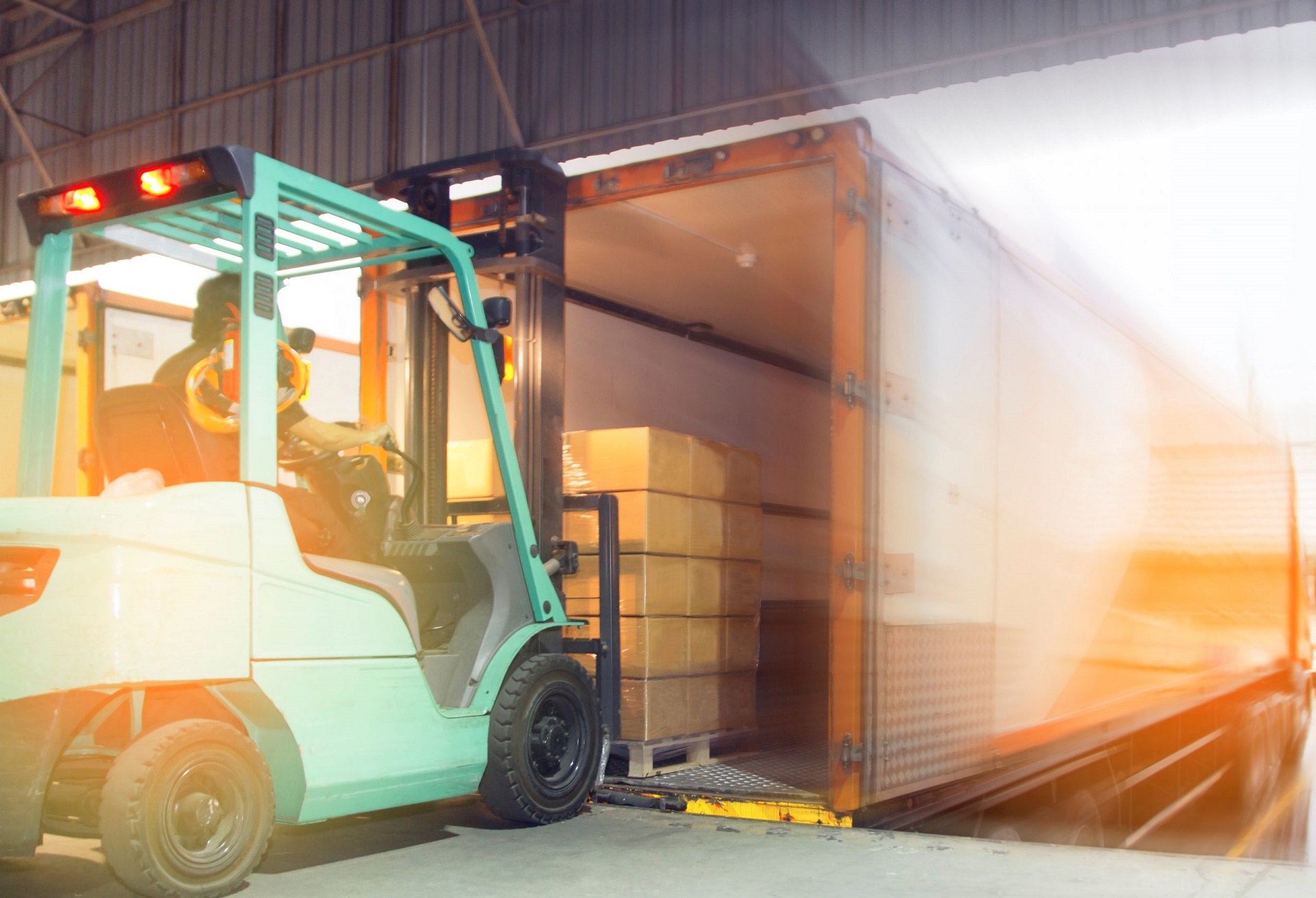 Freight transportation and Logistic warehouse, Forklift driver loading the shipment pallet into a truck container.