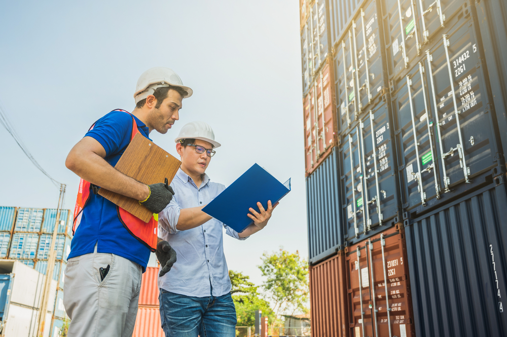 Foreman and dock worker staff working checking at Container cargo harbor holding clipboard. Business Logistics import export shipping concept.